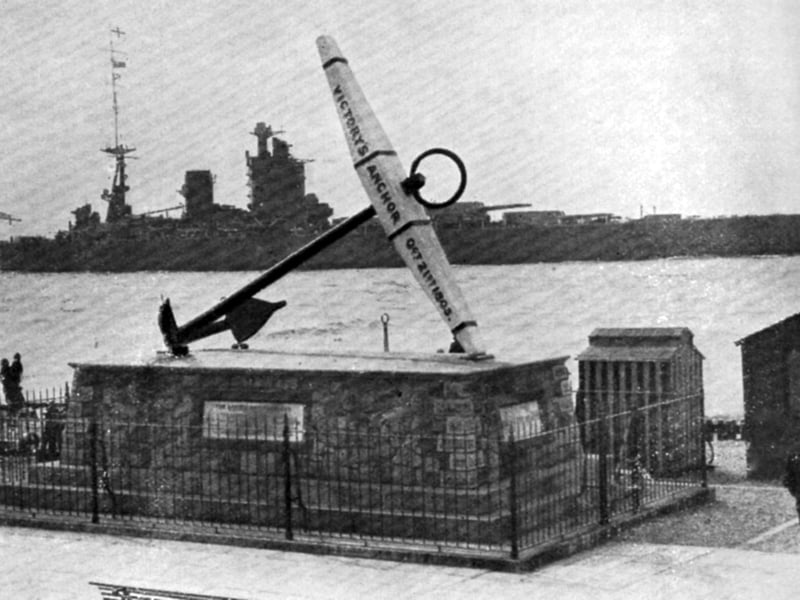 A beautifully posed photograph of the battleship HMS Nelson passing HMS Victory’s anchor.
