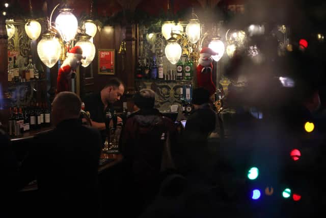 A barman pours a drink inside a dark pub. Picture: HOLLIE ADAMS/AFP via Getty Images