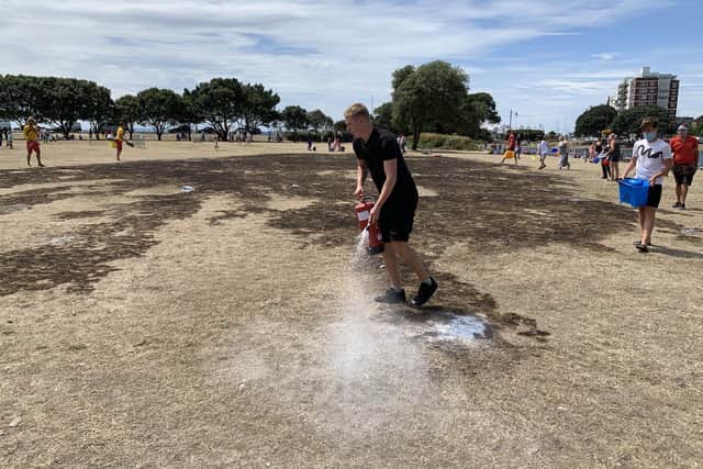 A man uses a fire extinguisher to fight the fire near Canoe Lake as people fill buckets of water to help quell the flames. Picture by Colin Farmery