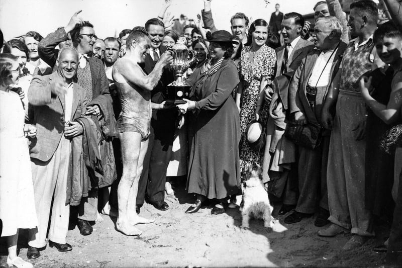 20th August 1936:  Mr C Rogers of the Gosport Swimming Club receives the trophy from Mrs Mortimer on arrival in Ryde after his winning swim from Southsea to the Isle of Wight, which he won by the narrow margin of 19 seconds.  (Photo by J. A. Hampton/Topical Press Agency/Getty Images)