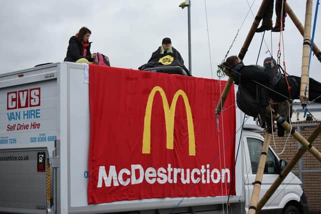Image issued by Animal Rebellion showing Animal Rebellion protesters suspended from a bamboo structure and on top of a van, being monitored by police officers, outside a McDonalds distribution site in Basingstoke, which is being blockaded to stop lorries from leaving the depot. Picture: Andrea Domeniconi/PA Wire