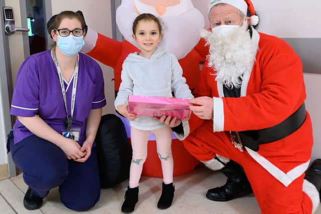 Sophia Ramalho, 5 receives a gift from Father Christmas (Dave Gosling) with Zoe Parton, play specialist at the children's emergency department.
Picture: Keith Woodland (181221-0)