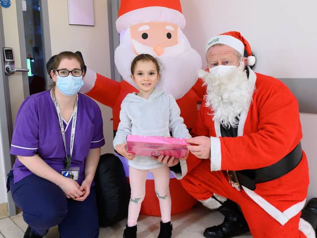 Sophia Ramalho, 5 receives a gift from Father Christmas (Dave Gosling) with Zoe Parton, play specialist at the children's emergency department.

Picture: Keith Woodland (181221-0)