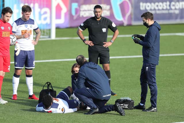 Godfrey Poku receives treatment for his knee injury prior to coming off during the first half of the FA Trophy tie against Notts County. Photo by Dave Haines