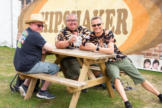 Friends Jim Motteram, Kevin Spindler and Gary Gomm enjoy a drink and some cards outside Hipshaker at The Isle Of Wight Festival 2022.