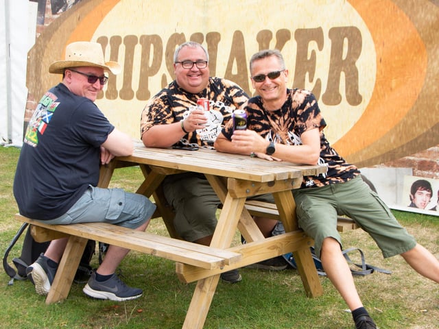Friends Jim Motteram, Kevin Spindler and Gary Gomm enjoy a drink and some cards outside Hipshaker at The Isle Of Wight Festival 2022.