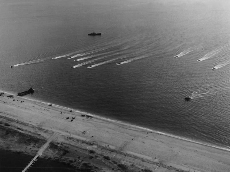 American troops and landing craft during practice landings at Slapton Sands, Devon, prior to D-Day. A formation of small LCVPs [Landing Craft, Vehicle, Personnel] are approaching the beach at speed where an LCT has already unloaded its cargo.