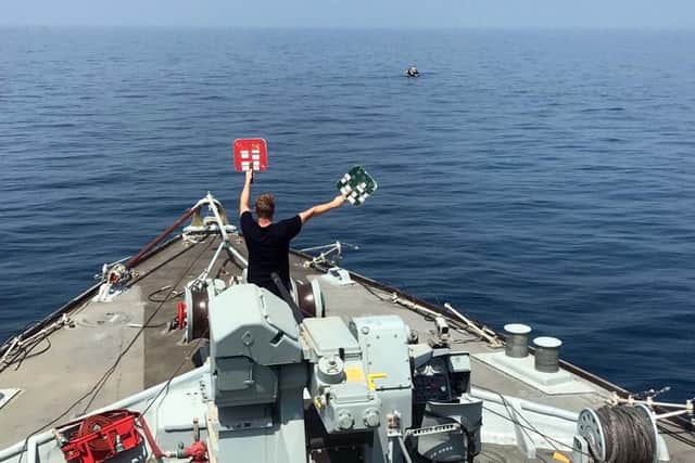 Teams signal to divers in the water from a Royal Navy minehunter. Photo: Royal Navy