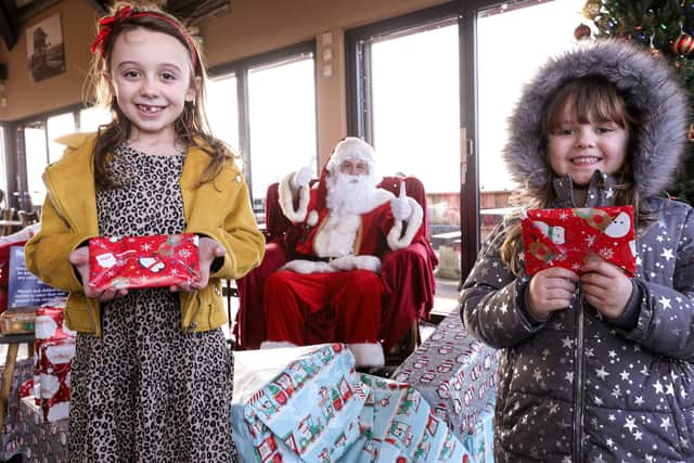 Renei Mackley, nine, left, and her sister, Pixie Smith, five, meet a socially-distanced Santa Claus at the Coffee Cup, Eastney Esplanade, Southsea. Picture: Chris Moorhouse (121220-16)