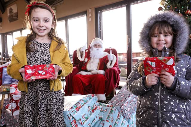 Renei Mackley, nine, left, and her sister, Pixie Smith, five, meet a socially-distanced Santa Claus at the Coffee Cup, Eastney Esplanade, Southsea. Picture: Chris Moorhouse      (121220-16)