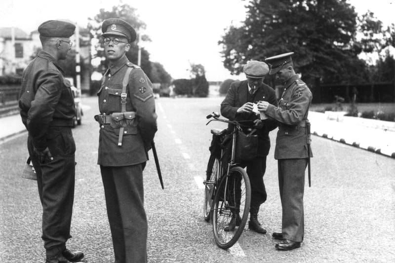 Military policemen checking the identity papers of a male civilian cyclist, 17.8.1943. This was the first day that special additional identity documents were required for anyone who wanted to go to the Southsea seafront area. These security measures were put in place in anticipation of preparations for D-Day. The location is the southern end of Festing Road, and what is now the Natural History Museum at Cumberland House can be seen in the left background.