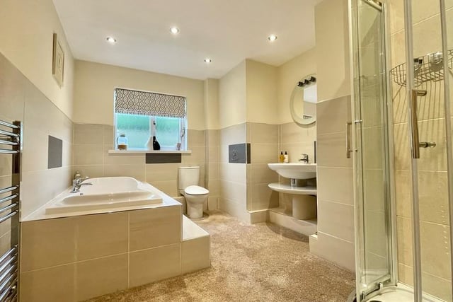 The family bathroom has a raised bath, a shower and a white suite.