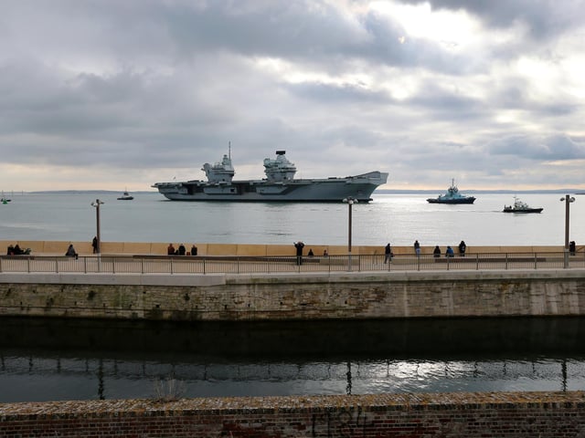 HMS Queen Elizabeth passes the newly reopened walkway on the sea defences at Long Curtain Moat, as she returns to Portsmouth Naval Base