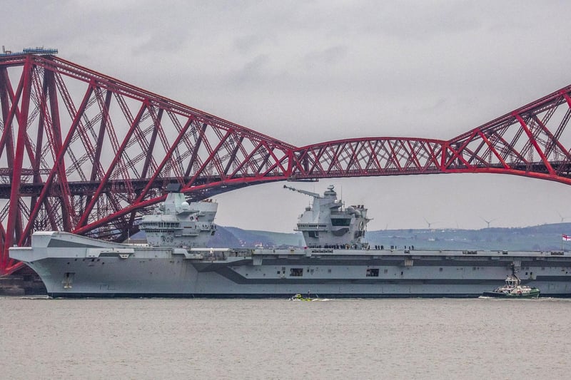 HMS Queen Elizabeth makes her way under the Forth Bridges as she prepares to dock at Rosyth dockyard for repairs, March 21 2024.