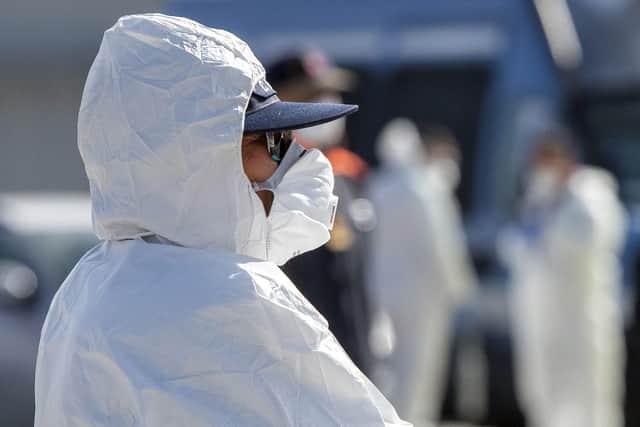 An Italian Red Cross' agent wearing protective suit and mask attends migrants rescued in the Mediterranean in February. Picture: Giovanni Isolino/AFP via Getty Images