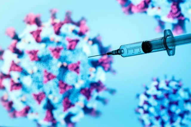 A syringe is pictured on an illustration representation of COVID-19, the disease caused by the novel coronavirus  (Photo by JOEL SAGET/AFP via Getty Images)