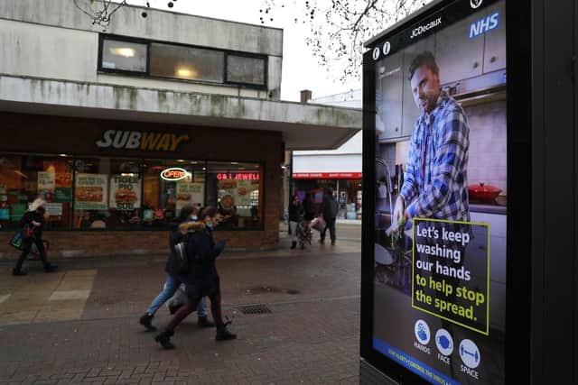 People pass a Government coronavirus sign as they make their way along Commercial Road in Portsmouth. Picture: Andrew Matthews/PA Wire
