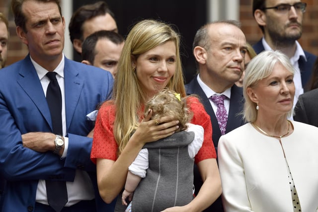 Carrie Johnson (centre), holding daughter Romy, alongside culture secretary Nadine Dorries (right), watch Prime Minister Boris Johnson as he reads a statement outside 10 Downing Street