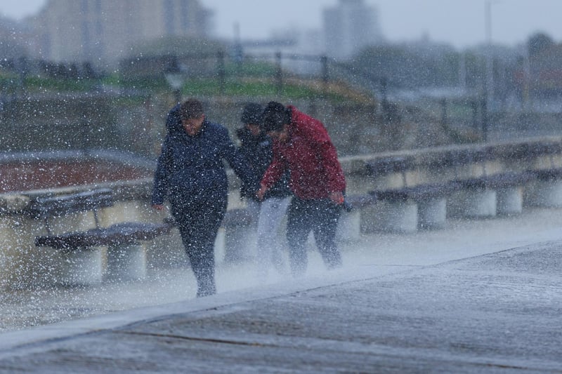 The stormy sea at high tide crashed waves onto footpaths as passer-by's did their best to get out the way