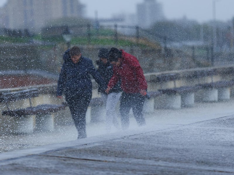 The stormy sea at high tide crashed waves onto footpaths as passer-by's did their best to get out the way