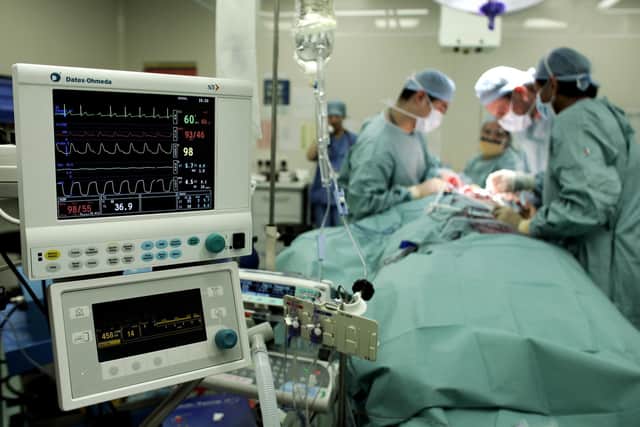 Surgeon carry out an operation to remove a tumour from a patient at an NHS hospital. Photo: Andrew Parsons/PA.