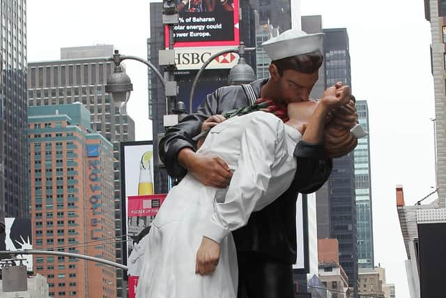 People gather beneath a 26-foot statue inspired by the iconic kiss between a nurse and a sailor in Times Square August 12, 2010 in New York City. Alfred Eisenstaedt took the famous photograph on V-J Day marking the end of World War II. August 14 will be the 65th anniversary of V-J Day and the famous kiss. (Photo by Mario Tama/Getty Images)