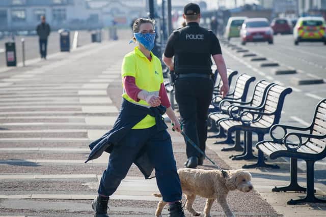 A woman wears a mask with police in the background in Southsea on March 27, 2020. Picture: Habibur Rahman