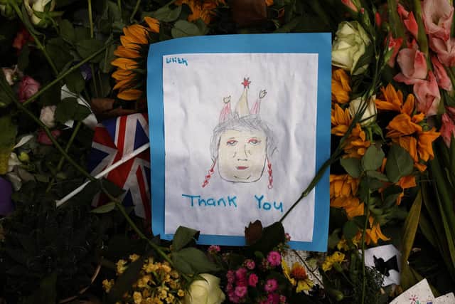 A child's hand-drawn image of Queen Elizabeth II lays among the thousands of flower bouquets that have been left in tribute to the queen, who died last week, on September 12, 2022 in London. Picture: Chip Somodevilla/Getty Images.