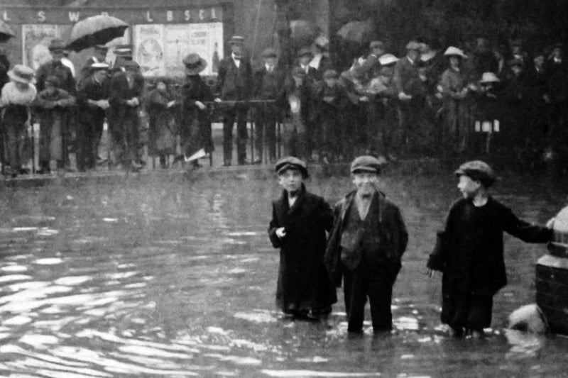 Flooding outside the goods sheds in Commercial Road.
The boy’s face in the centre says it all. Flooding in Commercial Road taken from inside the gates of the railway goods shed.