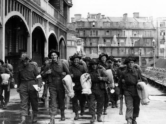 Soldiers walk along South Parade Pier to embark for Normandy.