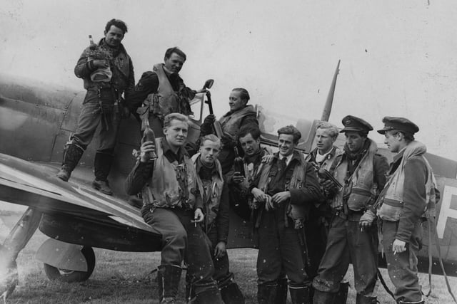 29th June 1944:  Pilots from a Spitfire Squadron, who have returned from a French attack, holding bottles of wine. (Photo by Harry Shepherd/Fox Photos/Getty Images)