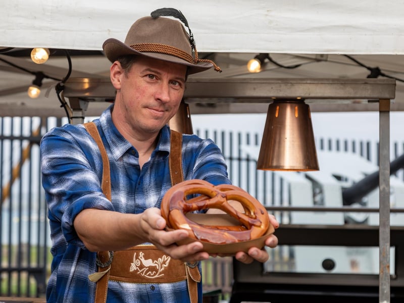 Oktoberfest visitor Paul Cobb (45) pauses for a pretzel provided by the Powder Monkey catering team. Picture: Mike Cooter (011023)