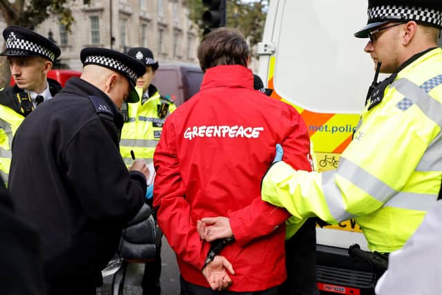 Police officers escorting a Greenpeace activist who was staging a sit-in at Downing Street in London on October 11, 2021. Picture: TOLGA AKMEN/AFP via Getty Images.