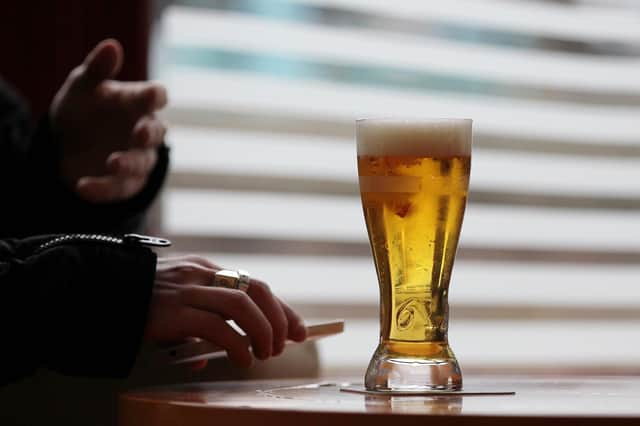 A man holds his smartphone next to a glass of beer (Photo by CHARLY TRIBALLEAU / AFP)