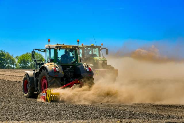 Farmers drive their tractors through a dry and dusty field. PIC: James Hardisty