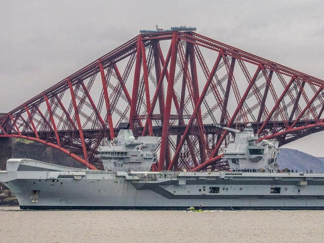 HMS Queen Elizabeth makes her way under the Forth Bridges as she prepares to dock at Rosyth dockyard for repairs, March 21 2024.