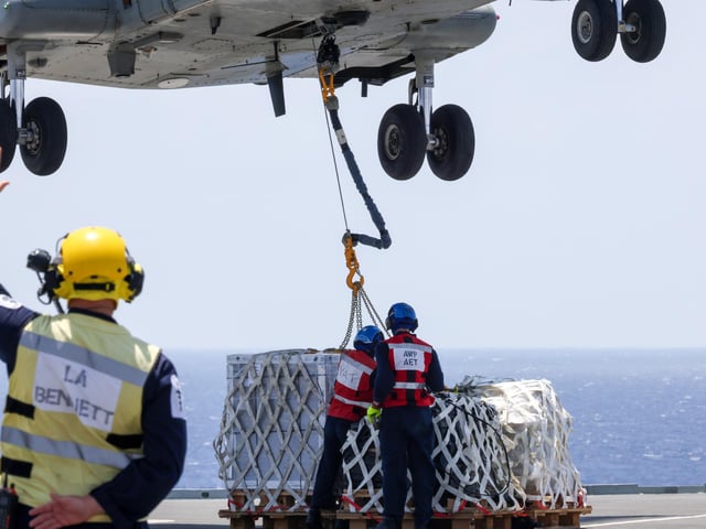 Air Engineers disconnect stores from a Merlin Mk 4 helicopter during a vertical replenishment from RFA Tidespring in 2021