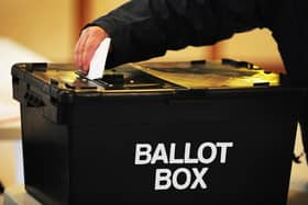 A voter placing a ballot paper in a ballot box at a polling station