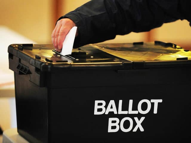 A voter placing a ballot paper in a ballot box at a polling station
