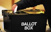 A voter placing a ballot paper in a ballot box at a polling station
