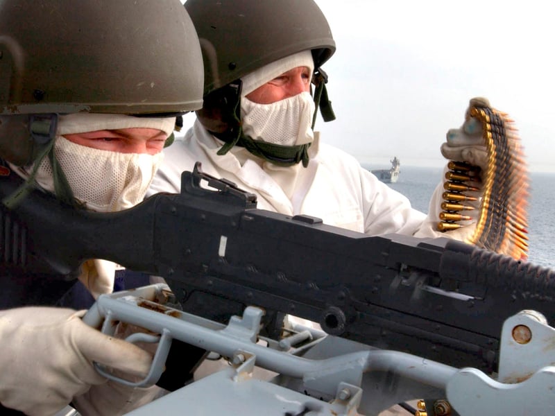 HMS Ark Royal in the Northern Arabian Gulf. Operator Maintainer (Above Water) Leigh Mears (19) from Huddersfield fires a GPMG (General Purpose Machine Gun) during weapon training on the carrier, he is assisted by Warrent Officer Stan Sayers. The helicopter carrier HMS Ocean is in the background. 06 Mar 2003.