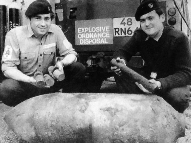 Two members of the Portsmouth and Medway Clearance Diving Team at HMS Vernon with the 250lb German bomb which was dredged up at Albert Johnson Quay. On the left LS(D) M O'Learey with some of the high explosive content of the bomb and AB C Carr with the fuse