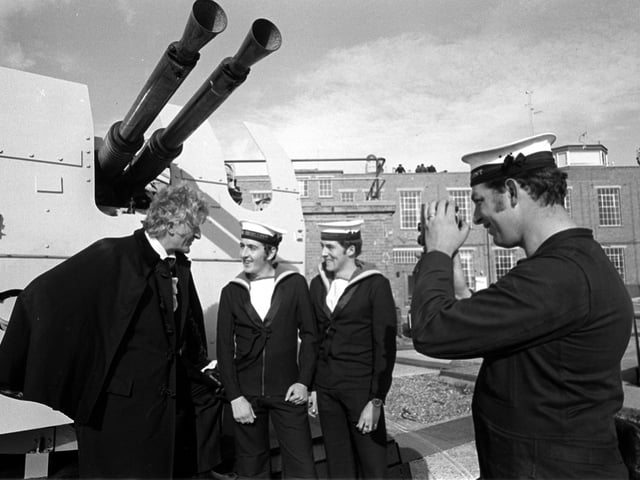 Taken 21st Oct 1971. Jon Pertwee pictured at Fraser Gunnery Range at Eastney where the BBC were filming Dr Who, The Sea Devils. Pictured with him L-R: Ordnance electrical mechanic Stephen Scholes from Leeds, control electrical mechanic Gerald Taylor from Wolverhampton (who were acting as extras in the filming), and David King from Chichester House, West Leigh is pictured taking a photo. Picture: The News 715097-2