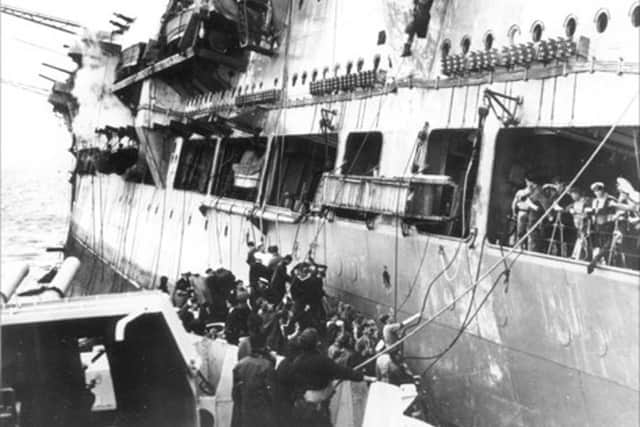 Crew from HMS Ark Royal pictured abandoning ship onto a waiting destroyer.