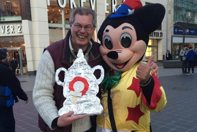 Simon Carter with the tinfoil FA Cup his daughter made him and Mickey Mouse, in Liverpool city centre on the day of the Liverpool v Exeter City third round replay in 2016.