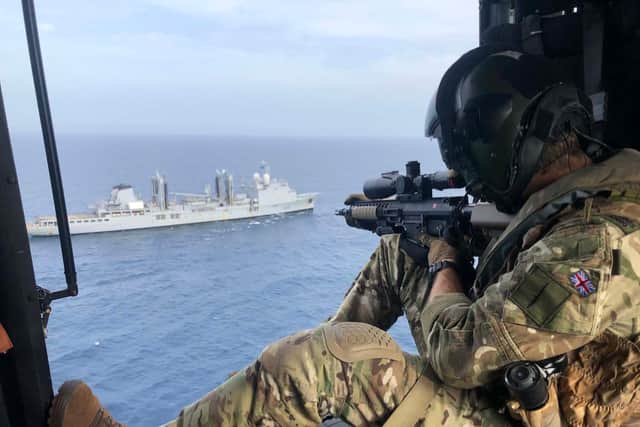 A Royal Marine sniper provides overwatch from a helicopter.