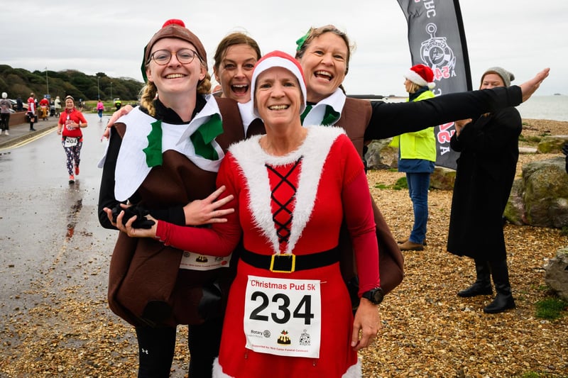 Four festive runners celebrate at the finish line of the Christmas Pud 5k, Stokes Bay, Gosport.