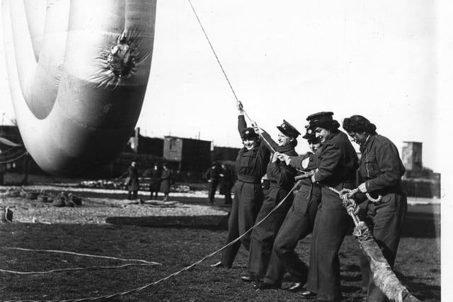 Members of the Women's Auxilliary Air Force tether a barrage balloon in Portsmouth in April 1942. Advertisements for balloon crews stipulated that women should be physically fit, have a minimum height of 5ft 2ins and be aged between 17 and 43. The News PP528