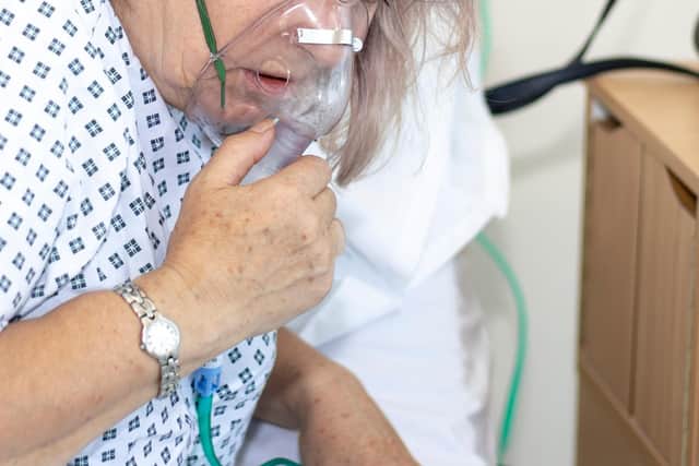Woman in hospital with breathing difficulties using a resperation mask.