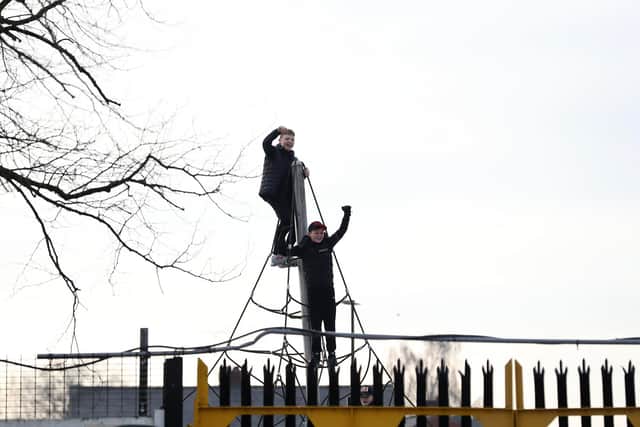 Spectators perch on a climbing frame to watch Chorley's FA Cup win against Derby. Pic: Martin Rickett/PA Wire.